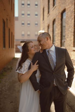 Candid moments between a couple sharing laughter in a sunlit brick corridor.