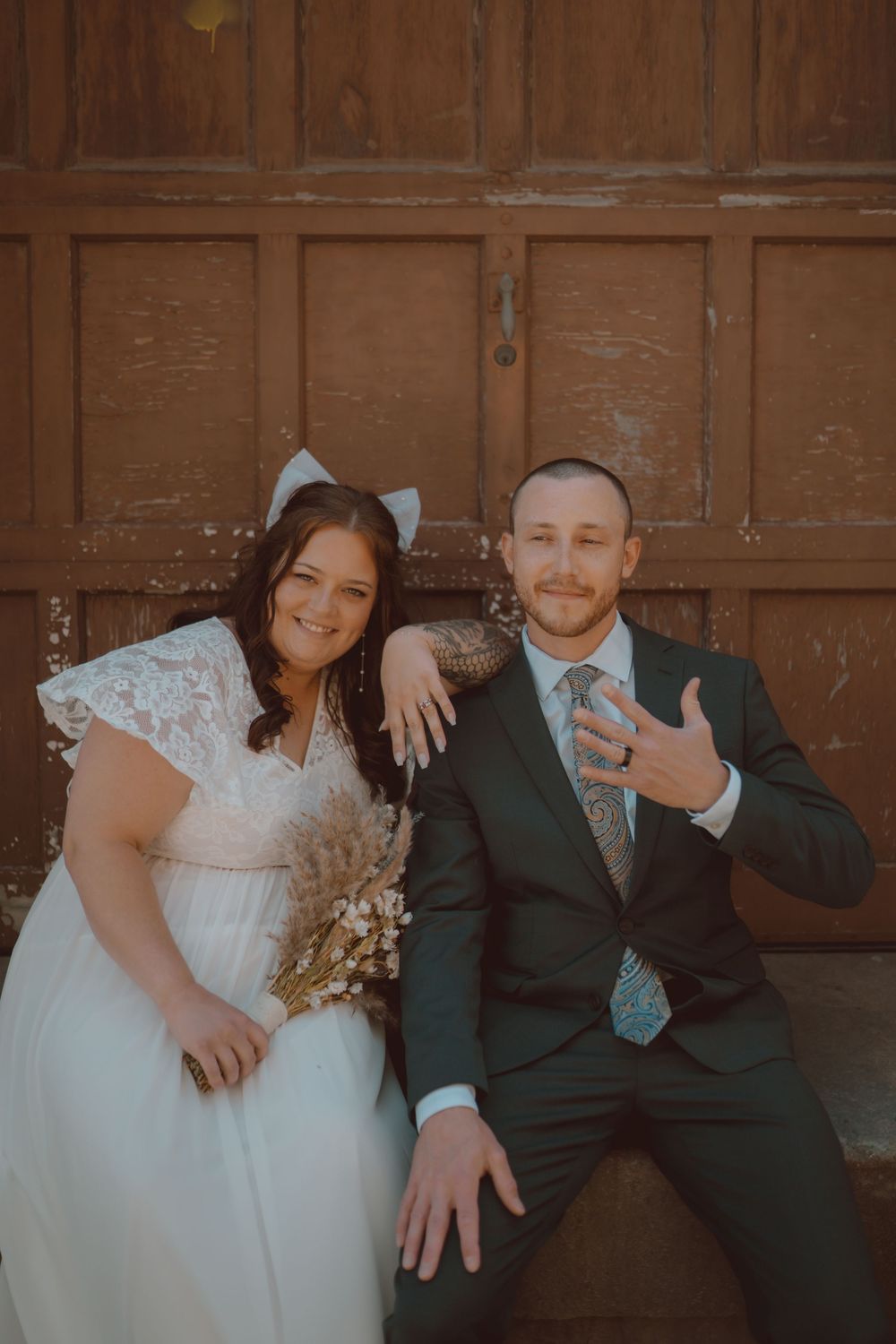 Newlyweds share playful moments against a rustic wooden backdrop during their wedding photoshoot.