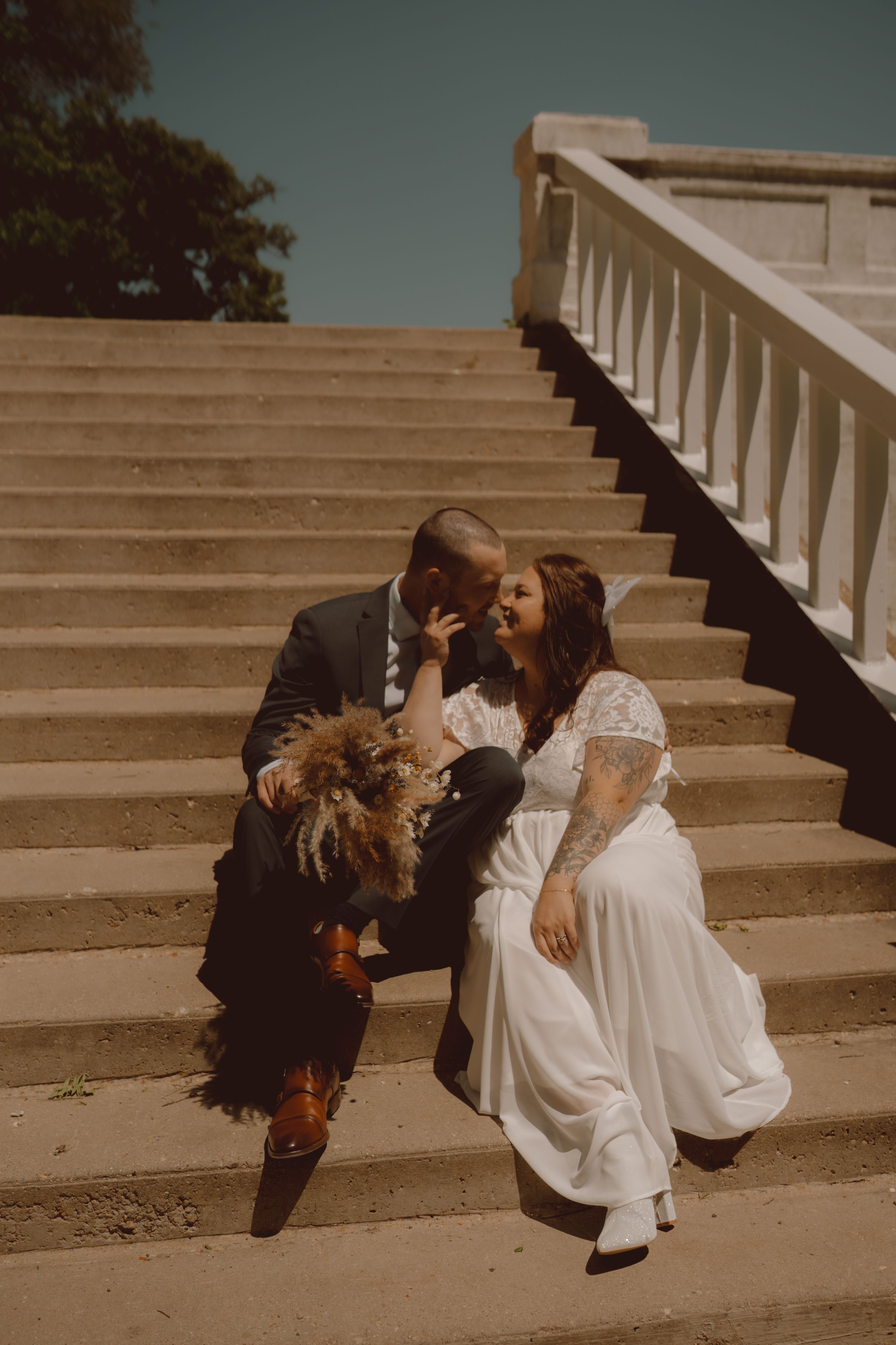 Romantic wedding photoshoot on concrete steps with dramatic lighting and artistic poses.