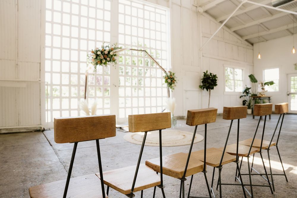 Modern minimalist wedding venue with wooden chairs and white walls with lattice windows.
