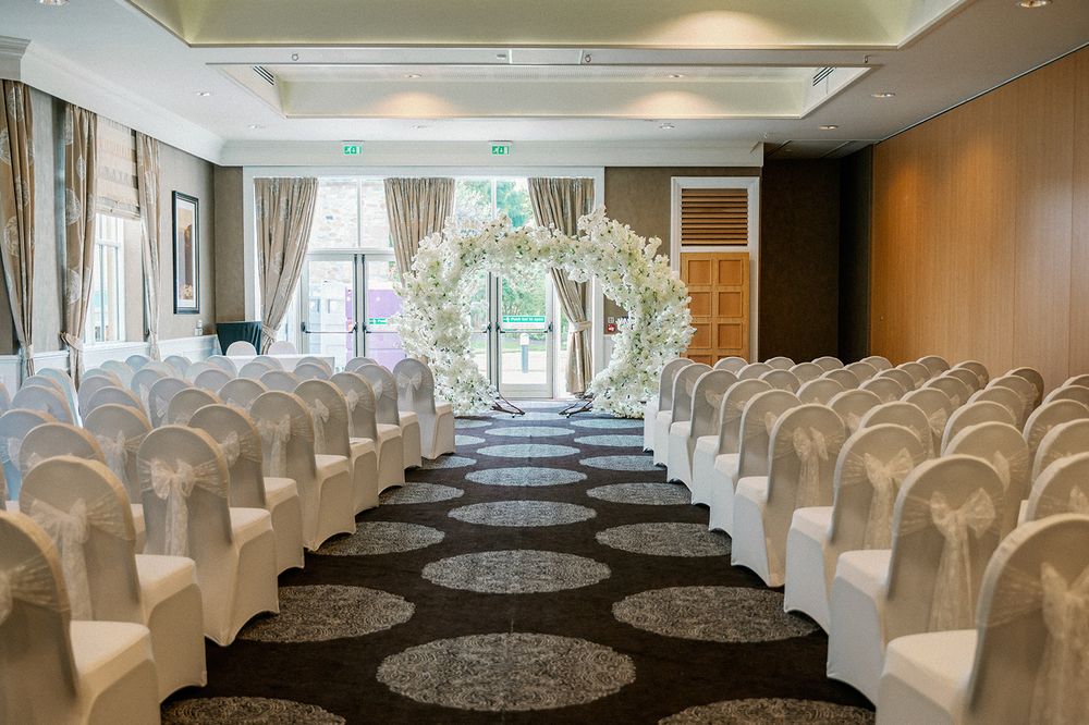 An elegant wedding reception hall set up with white chairs and round tables.