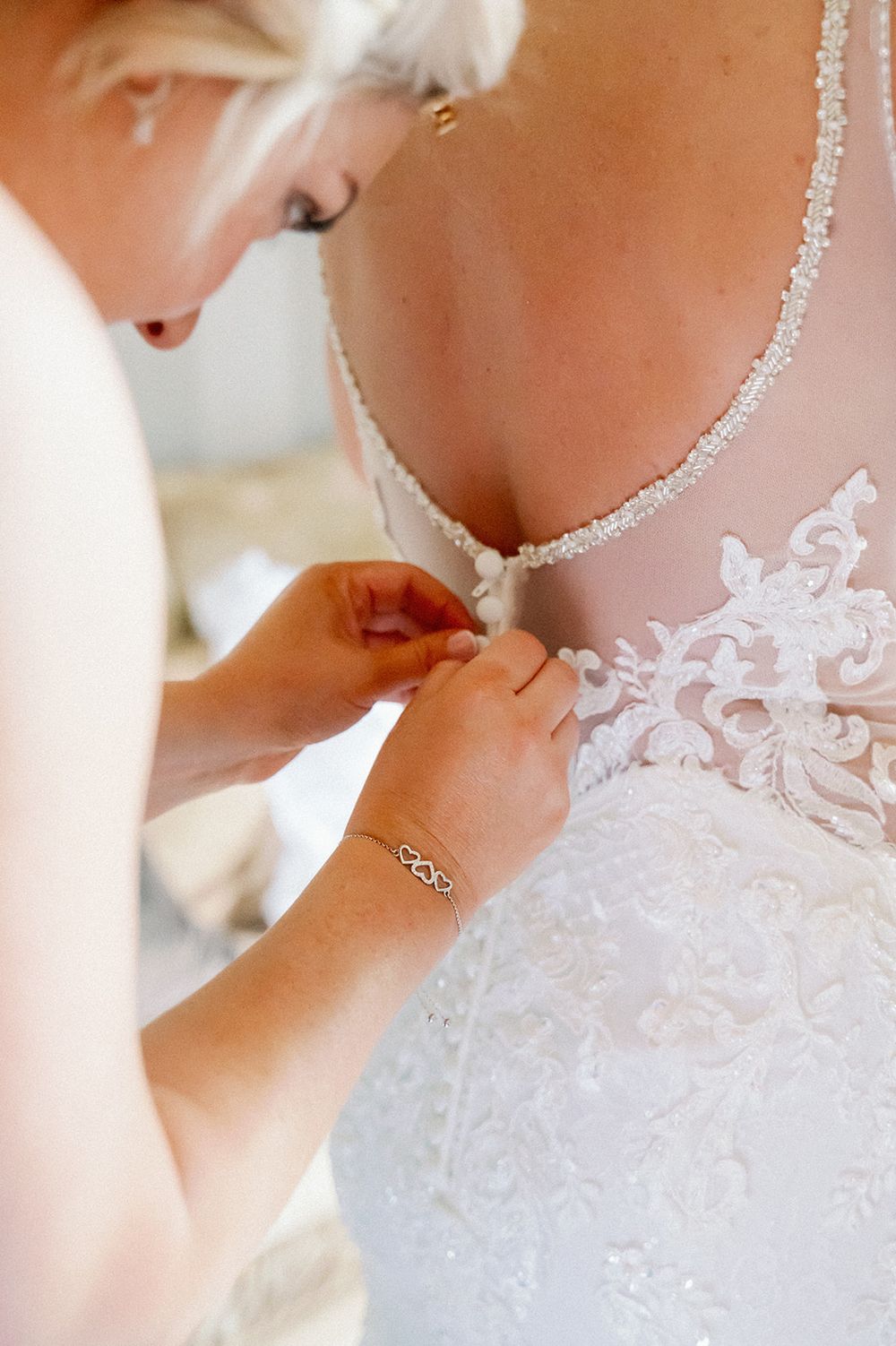 Close-up detail of delicate lace and beading on a white wedding dress.