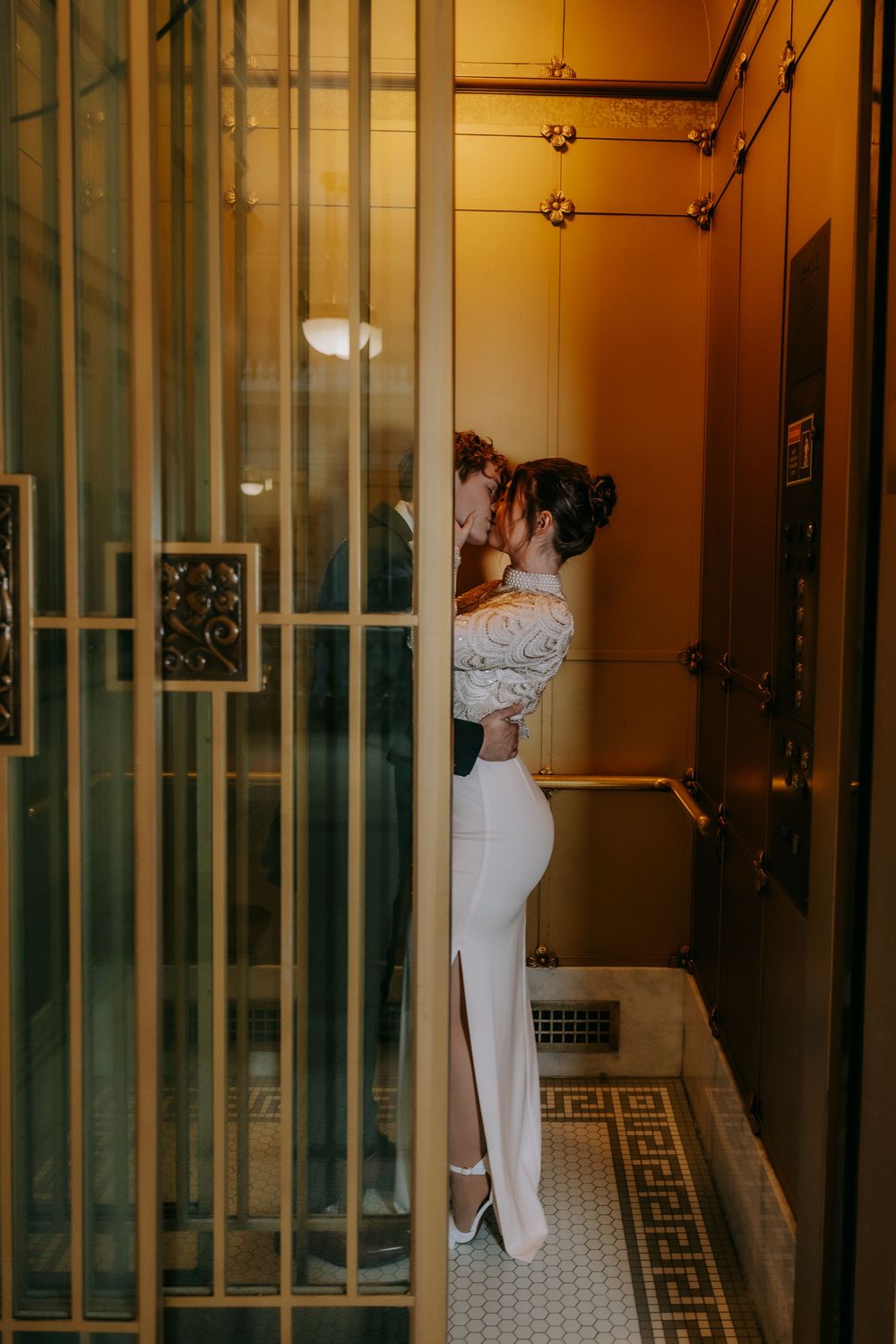 Romantic moment captured in an industrial elevator hallway with gold lighting.