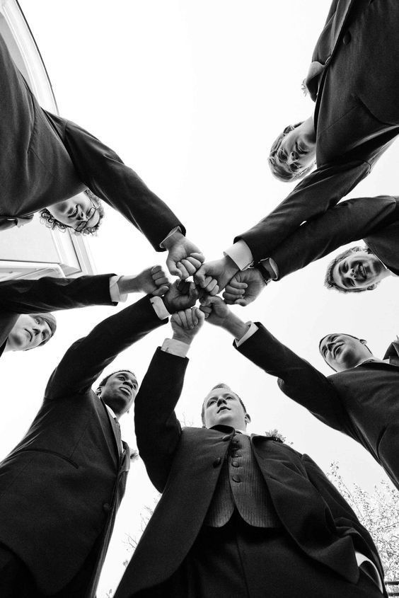 Black and white low angle view of business colleagues in suits joining hands in a team unity circle formation.