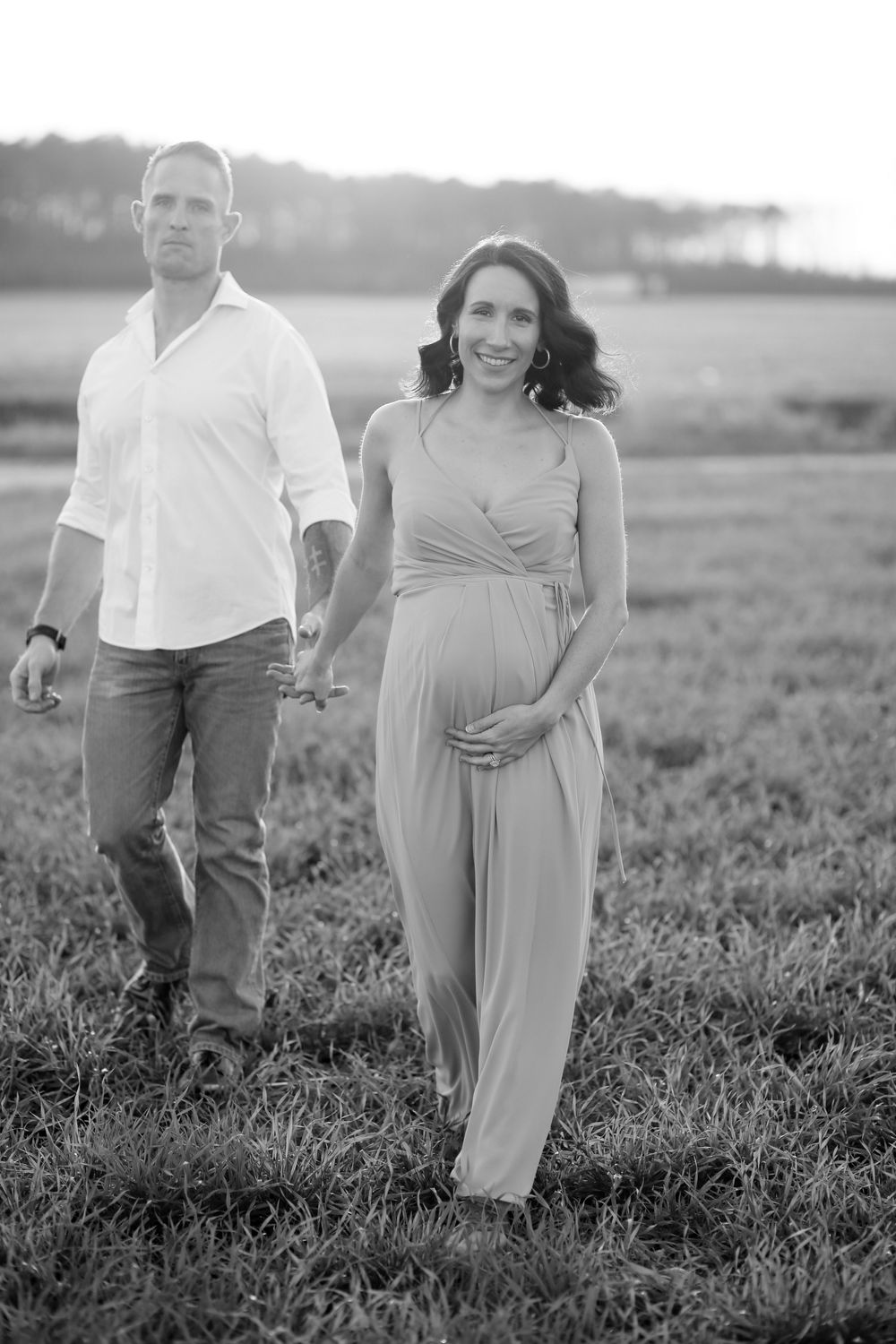 Expecting mother holding baby bump during a glowing maternity photography session with natural light in North Carolina.
