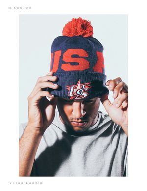 Man wearing navy USA pom beanie hat with red pompom and USA Baseball logo.