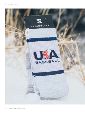 USA Baseball white and navy Strideline socks displayed in snow with dry grass background.