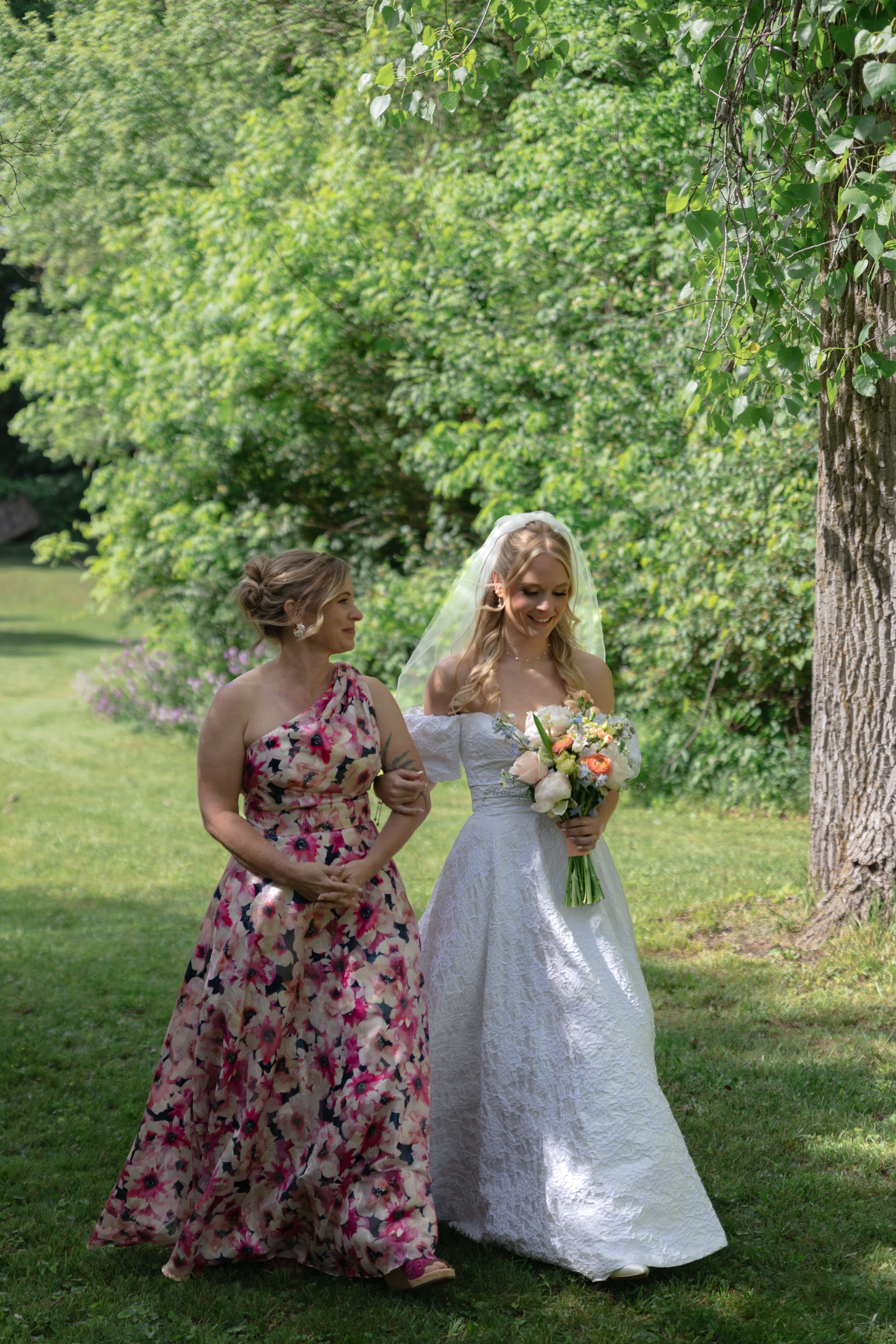Two guests walking through a lush garden area during an outdoor wedding celebration.