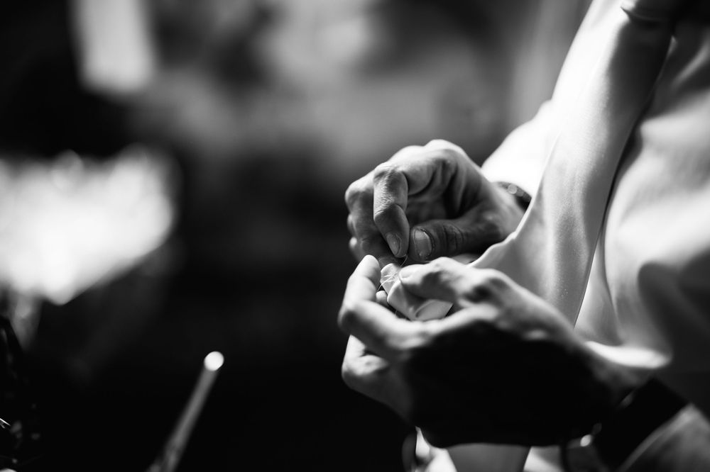 Black and white closeup of hands gently cupping something in a contemplative gesture.