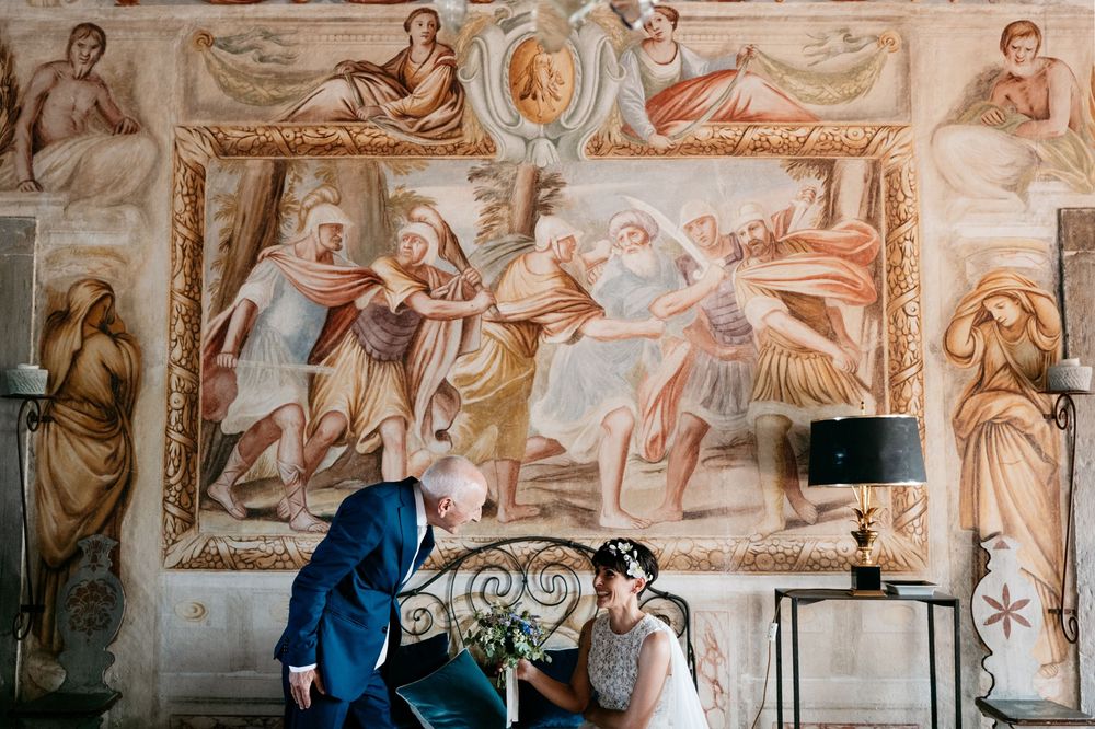 Wedding ceremony venue with classical fresco paintings and ornate architectural details.