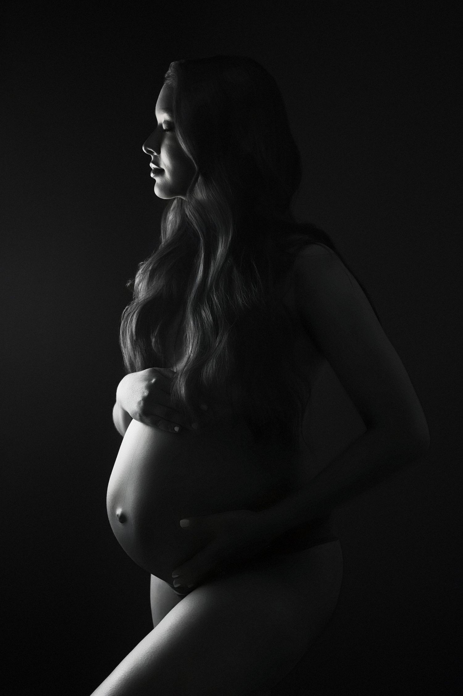 A maternity photoshoot in a bright white room features soft, intimate moments in polka dot attire.
