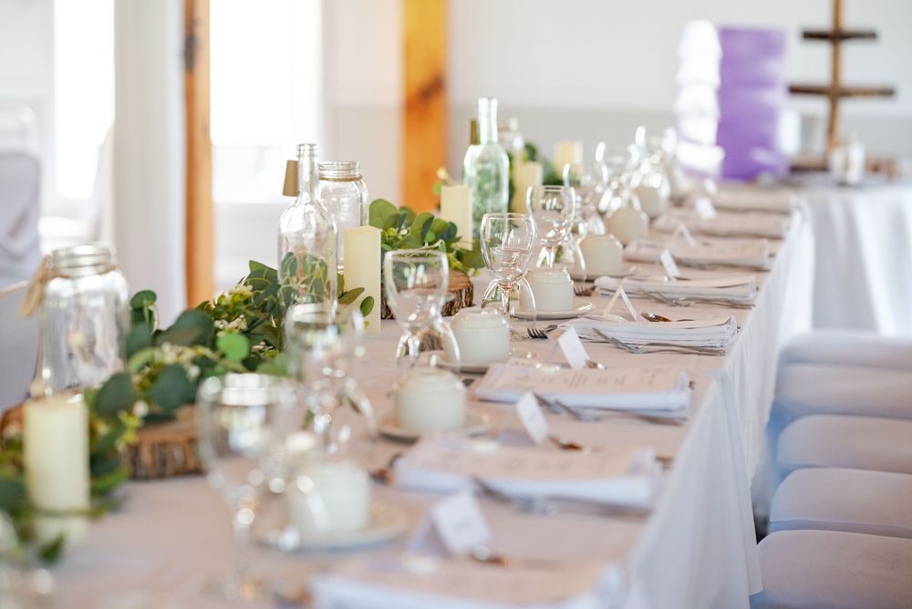 Elegant wedding reception table setting with greenery garland and candle centerpieces.