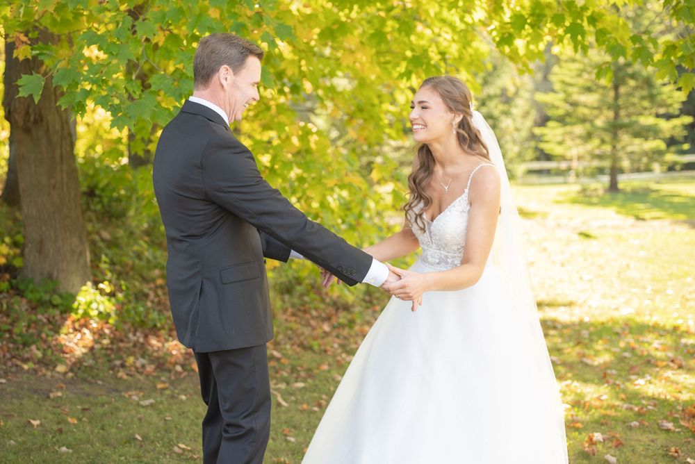 Couple shares first look moment in beautiful fall foliage setting.