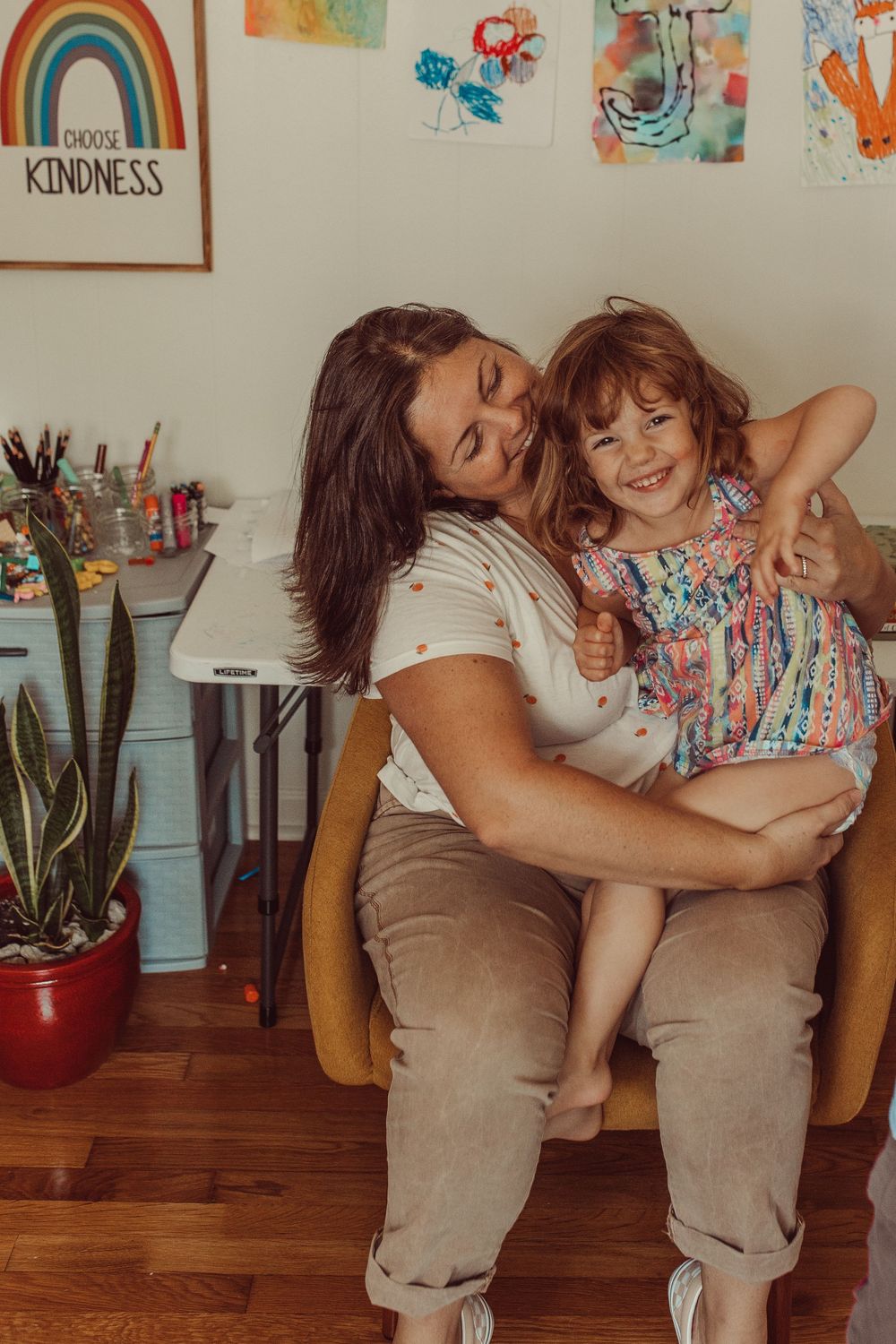A heartwarming embrace shared in a cozy room with art and plants, displaying pure joy and affection. WHITNEY POPP, Popp Photography