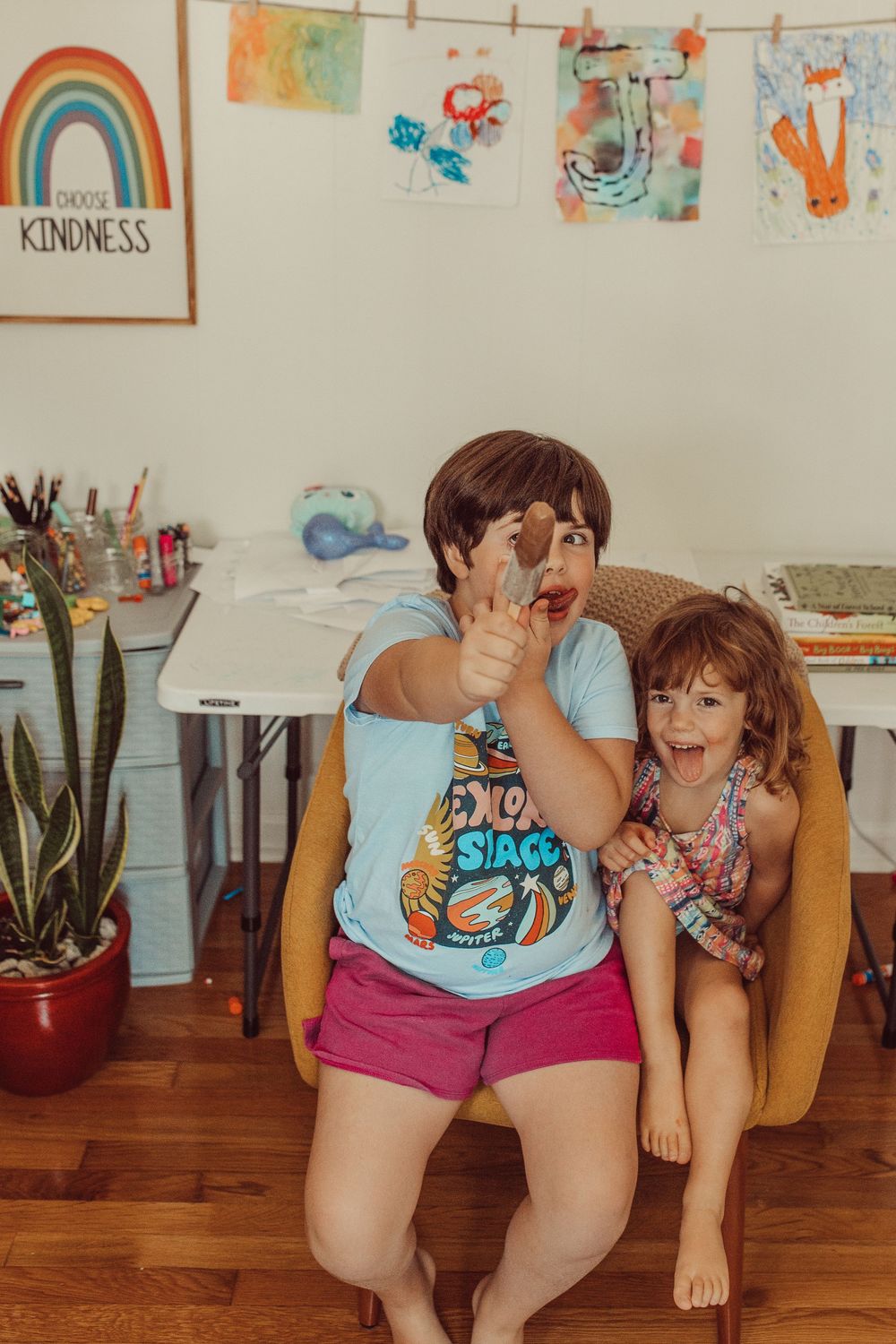 A playful scene in a home art room with a rainbow drawing on the wall and artwork display hanging on string. WHITNEY POPP, Popp Photography