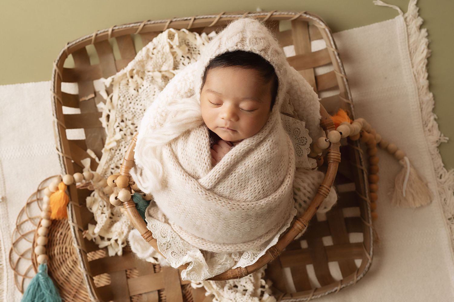 Peaceful newborn sleeping in beige wrap on woven wooden basket bed.