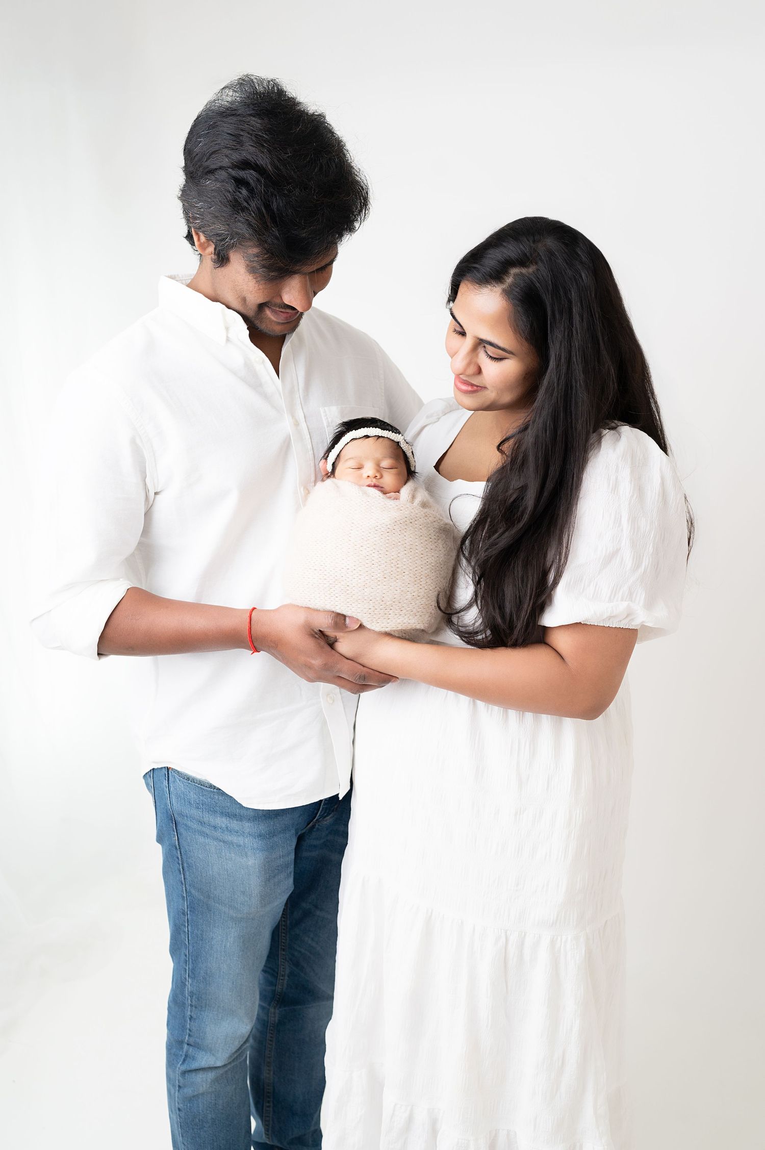 Intimate family photo series with parents in white and denim against minimal white background.