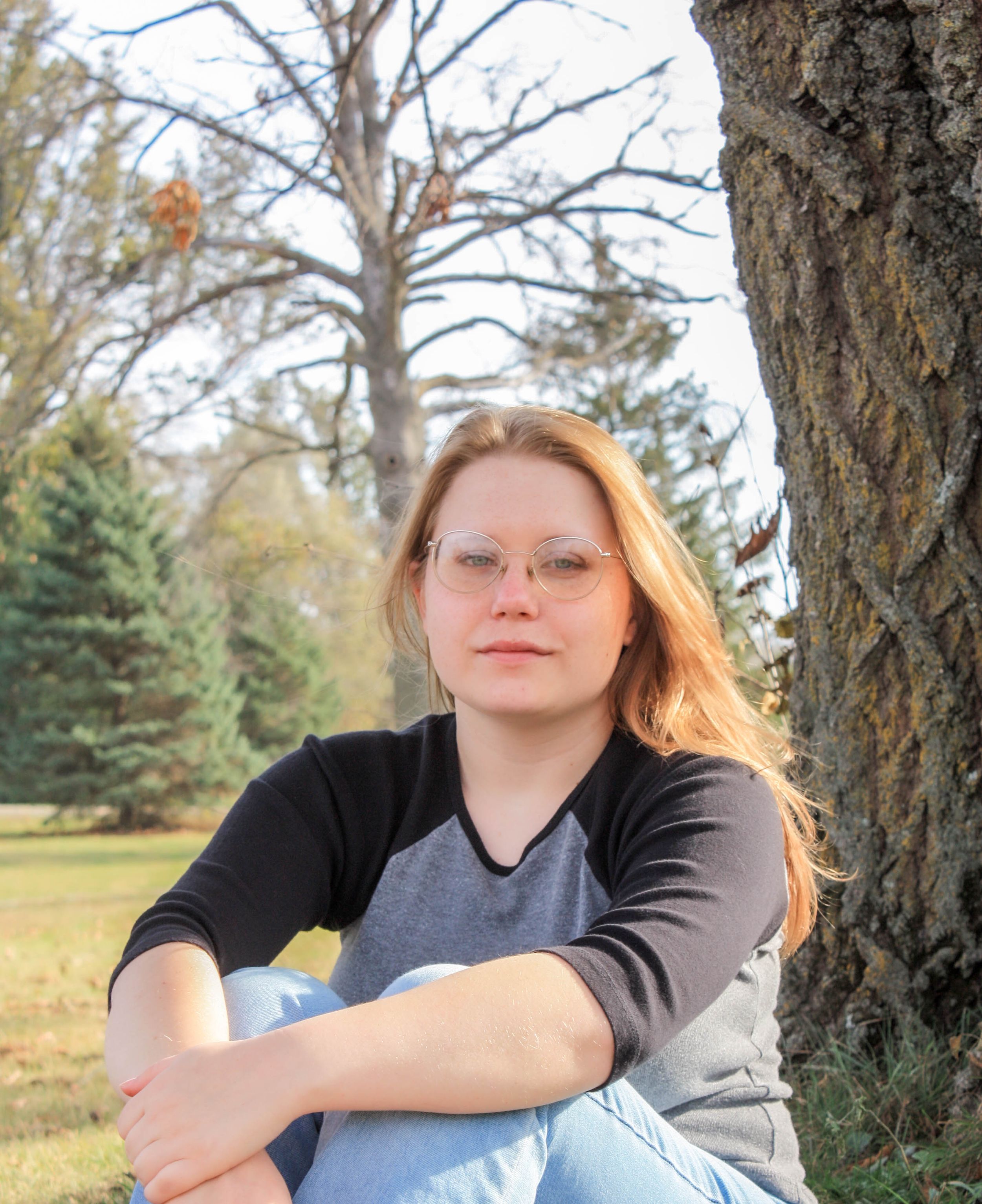 Outdoor portrait session among bare trees in casual attire.
