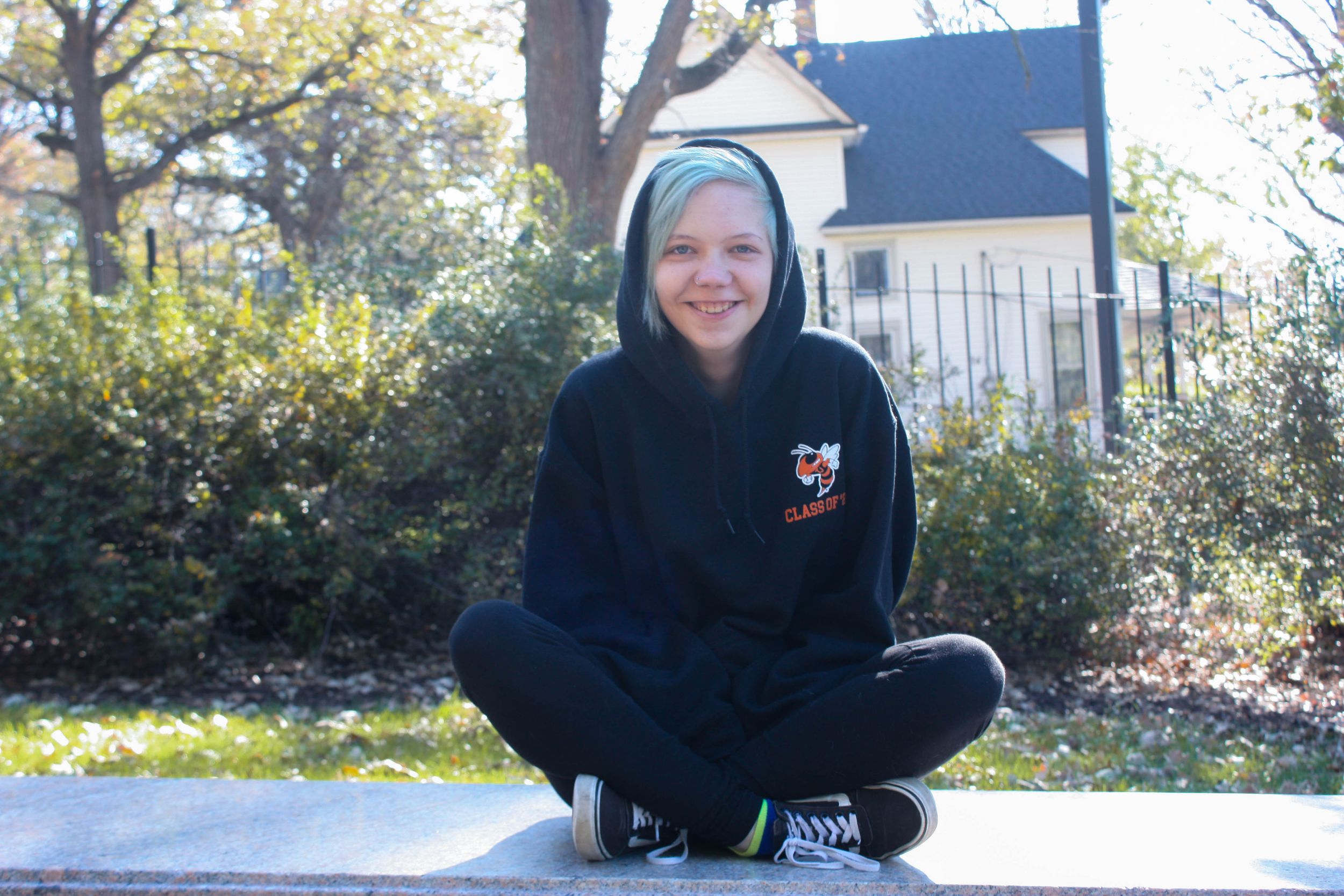 Person in black hoodie sitting outside during fall season.