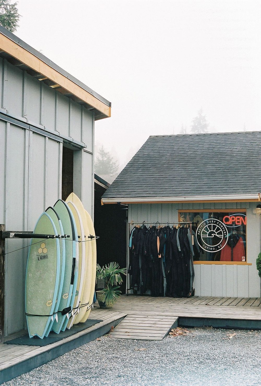 Surfboards lined up against a beach shop with clothing racks visible through the window.