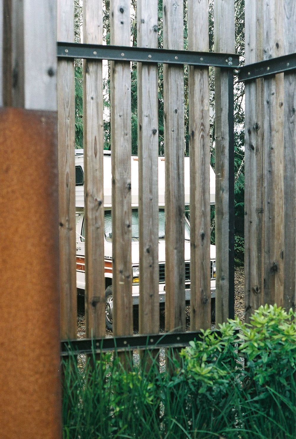 A wooden fence gate with vertical slats in a garden setting.