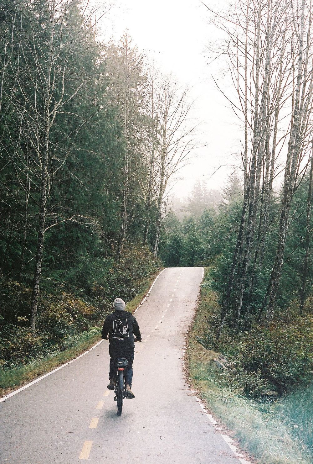 Motorcyclist rides down a winding forest path on an autumn day.