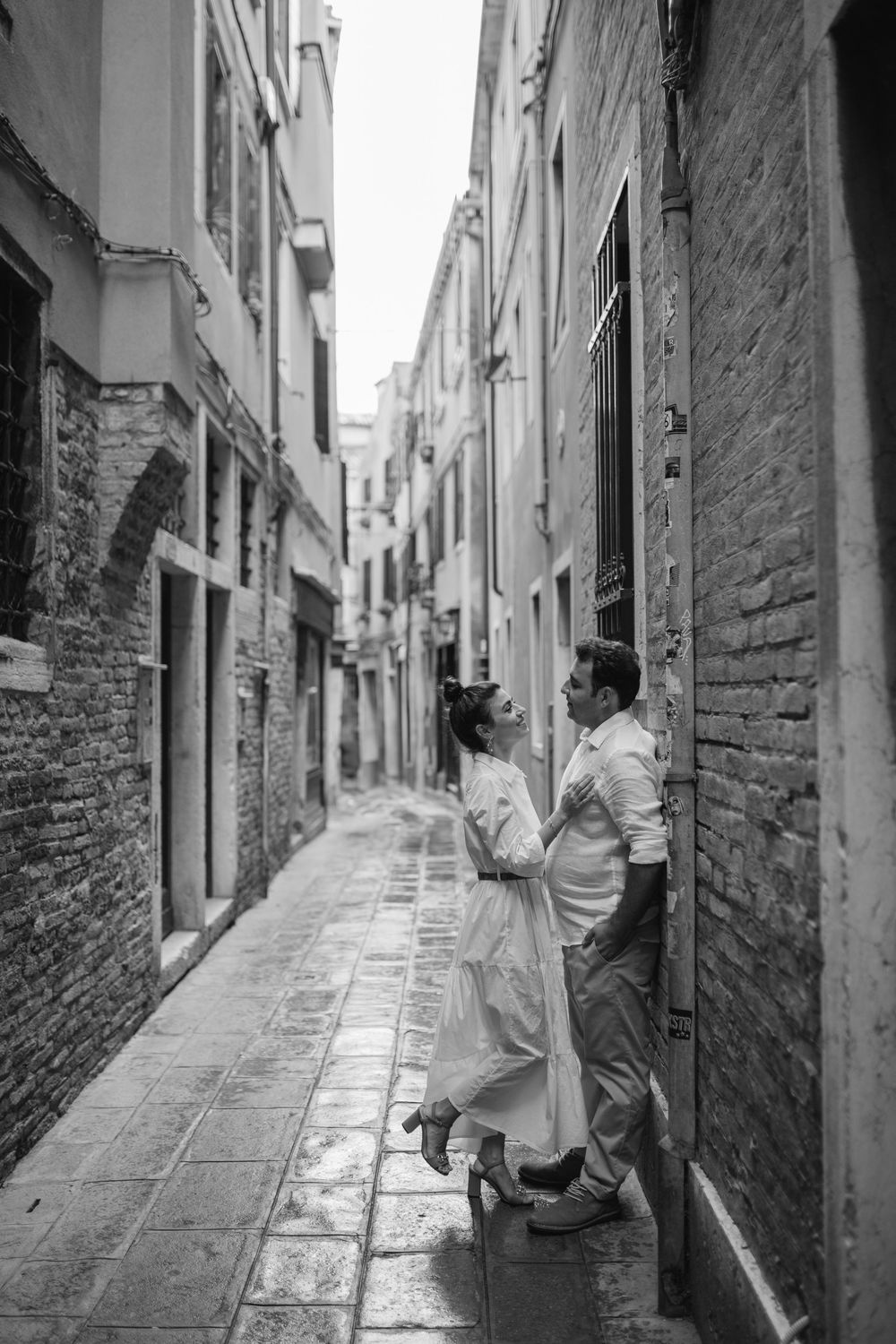 A romantic moment captured in a narrow Venice alleyway with traditional brick architecture.