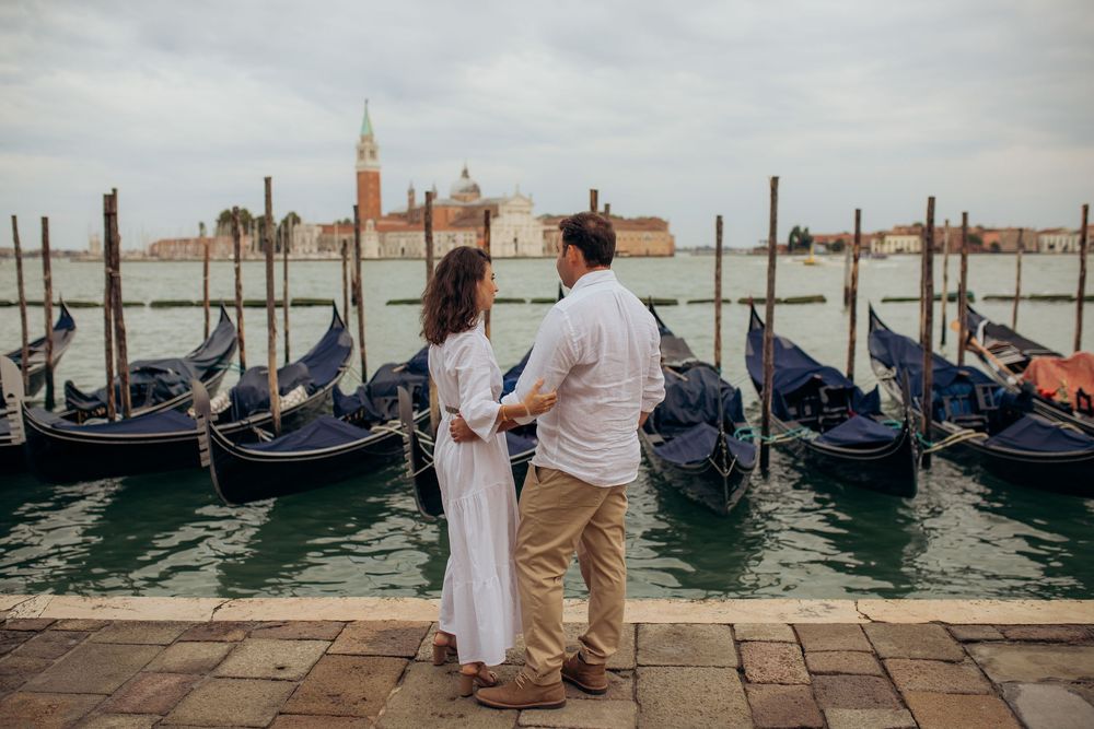 Couple admiring the view of gondolas on the Grand Canal in Venice.