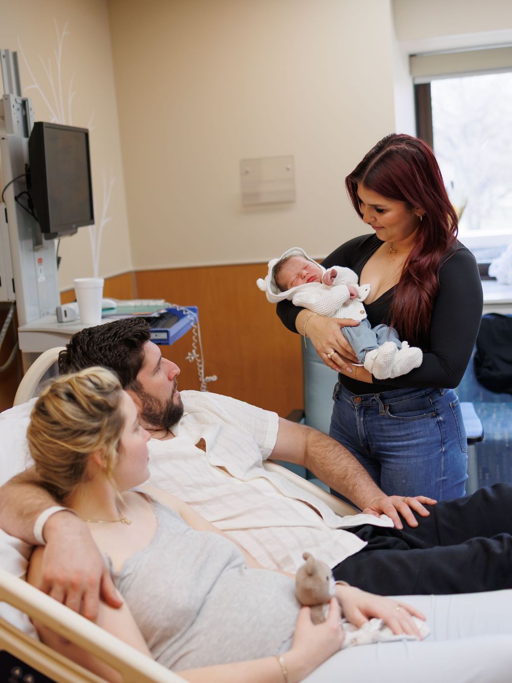 Medical scene showing new parents in a hospital room with their newborn baby during an intimate family moment.