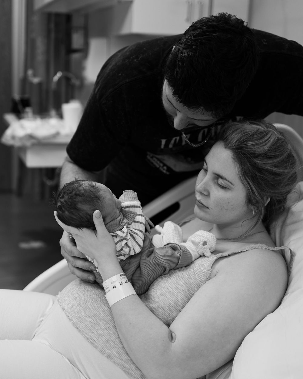 A tender moment captured in black and white as a newborn baby is cradled in the hospital.