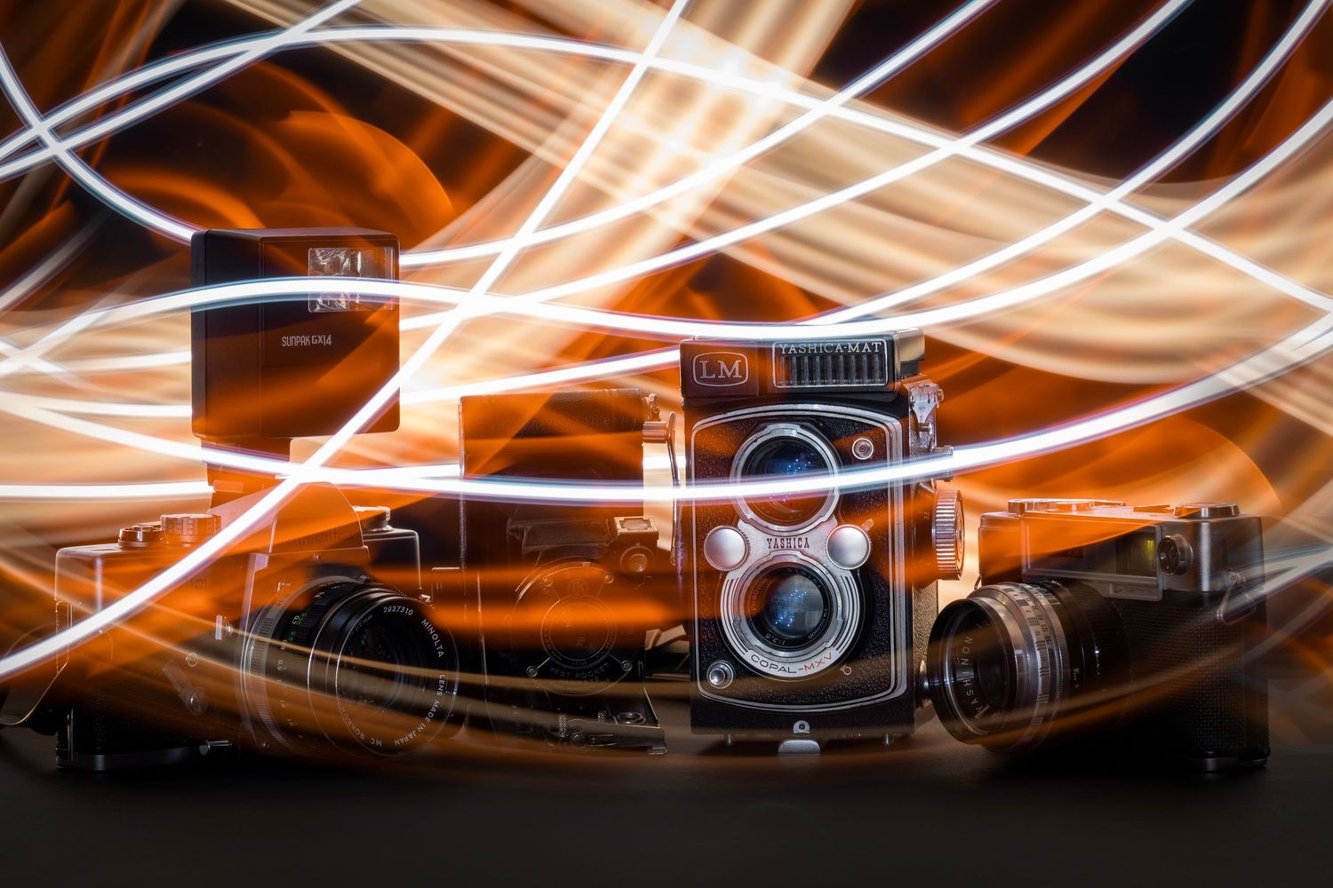 Vintage film cameras on display with swirling white and orange light trails creating a dramatic, high-energy backdrop.