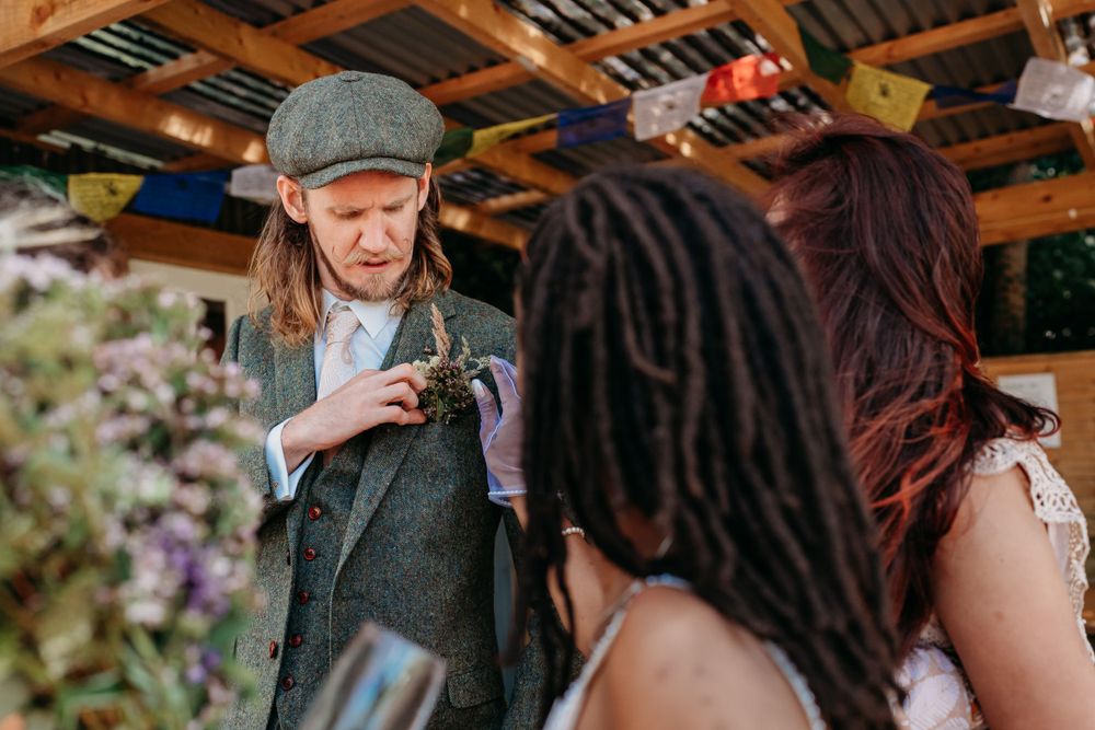 People socialize and chat at an outdoor gathering under a wooden pergola with warm rustic lighting.