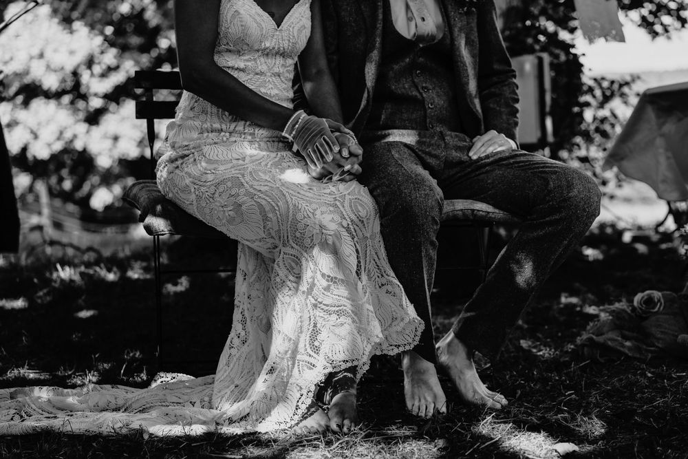 Black and white photo of lace wedding dress details and boots showing contrasting styles at outdoor photoshoot.