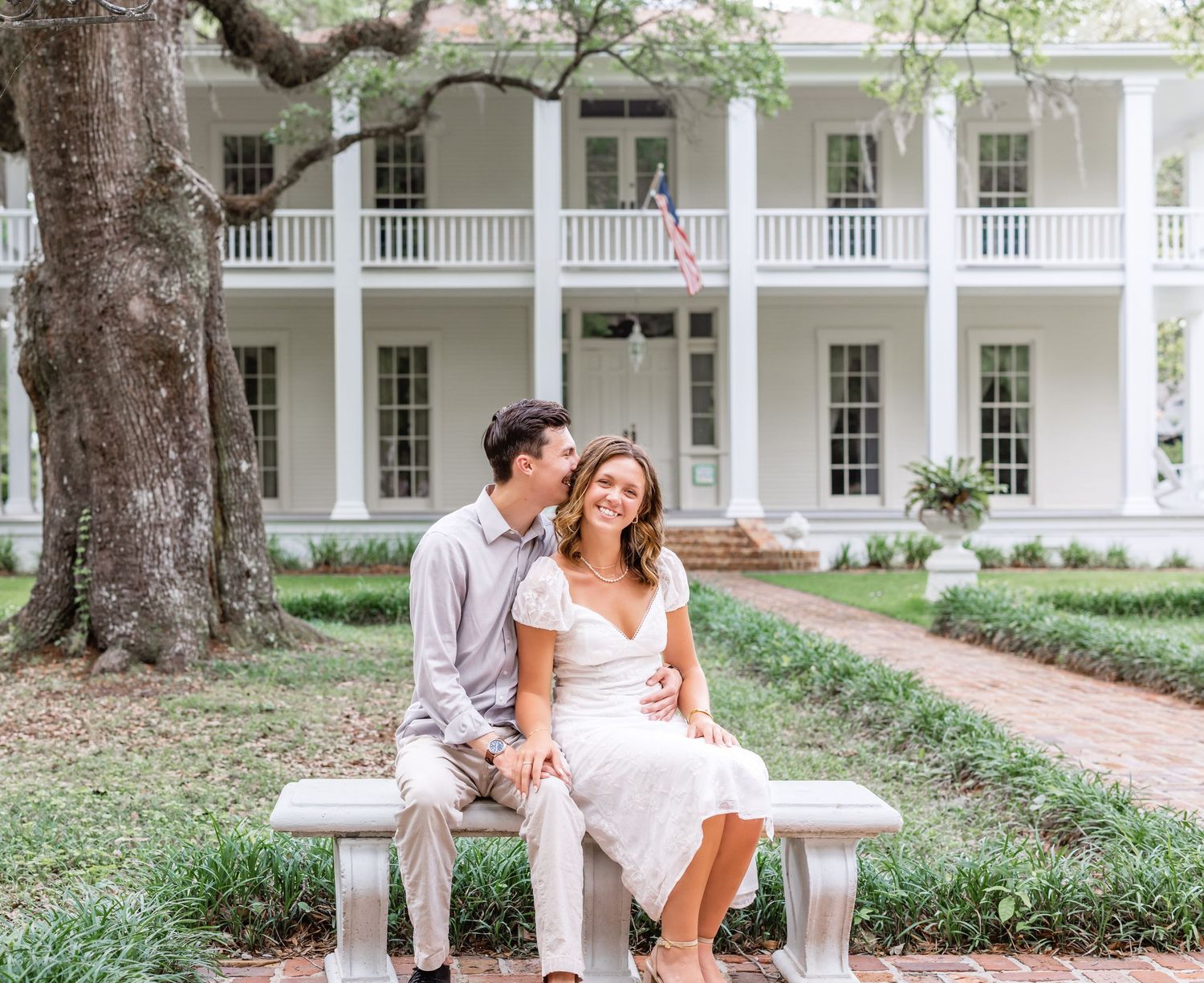 A series of romantic photos of a couple sitting on a bench in front of a white colonial style mansion.