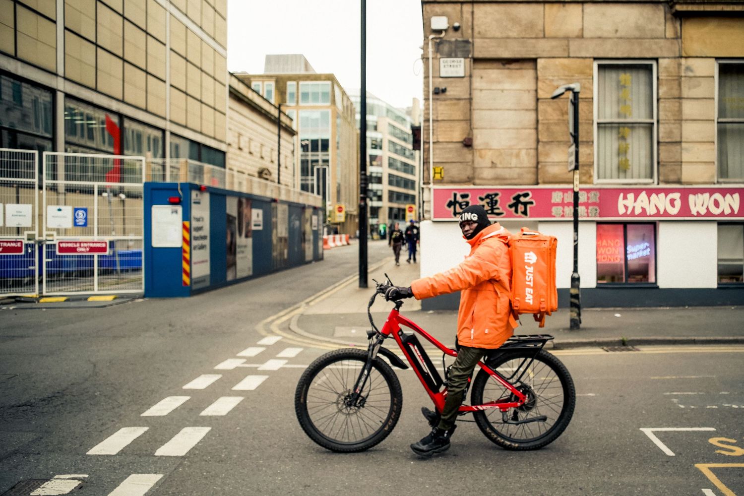 Urban street scene with delivery cyclist waiting at intersection.