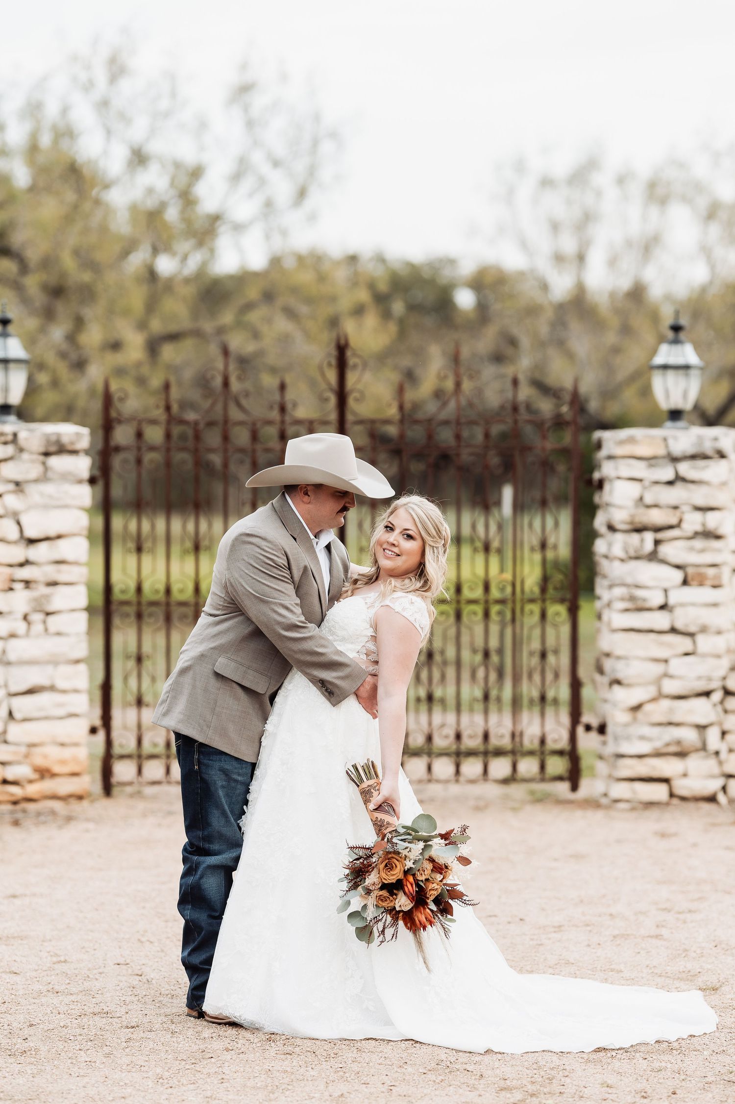 A romantic wedding portrait in front of a rustic stone gate with lanterns.