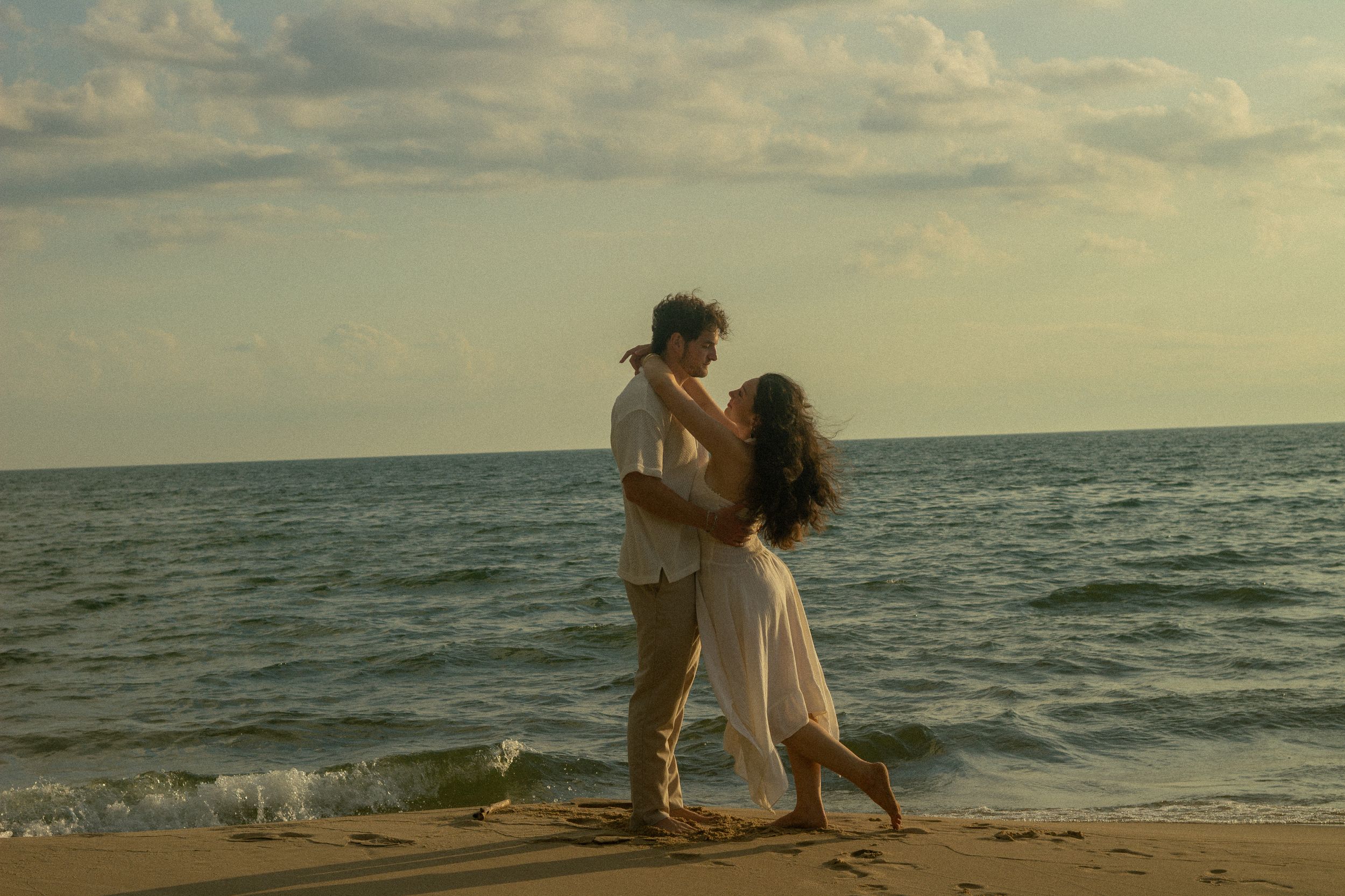 A couple embraces and spins on the beach for couples photos in Saugatuck, Michigan.