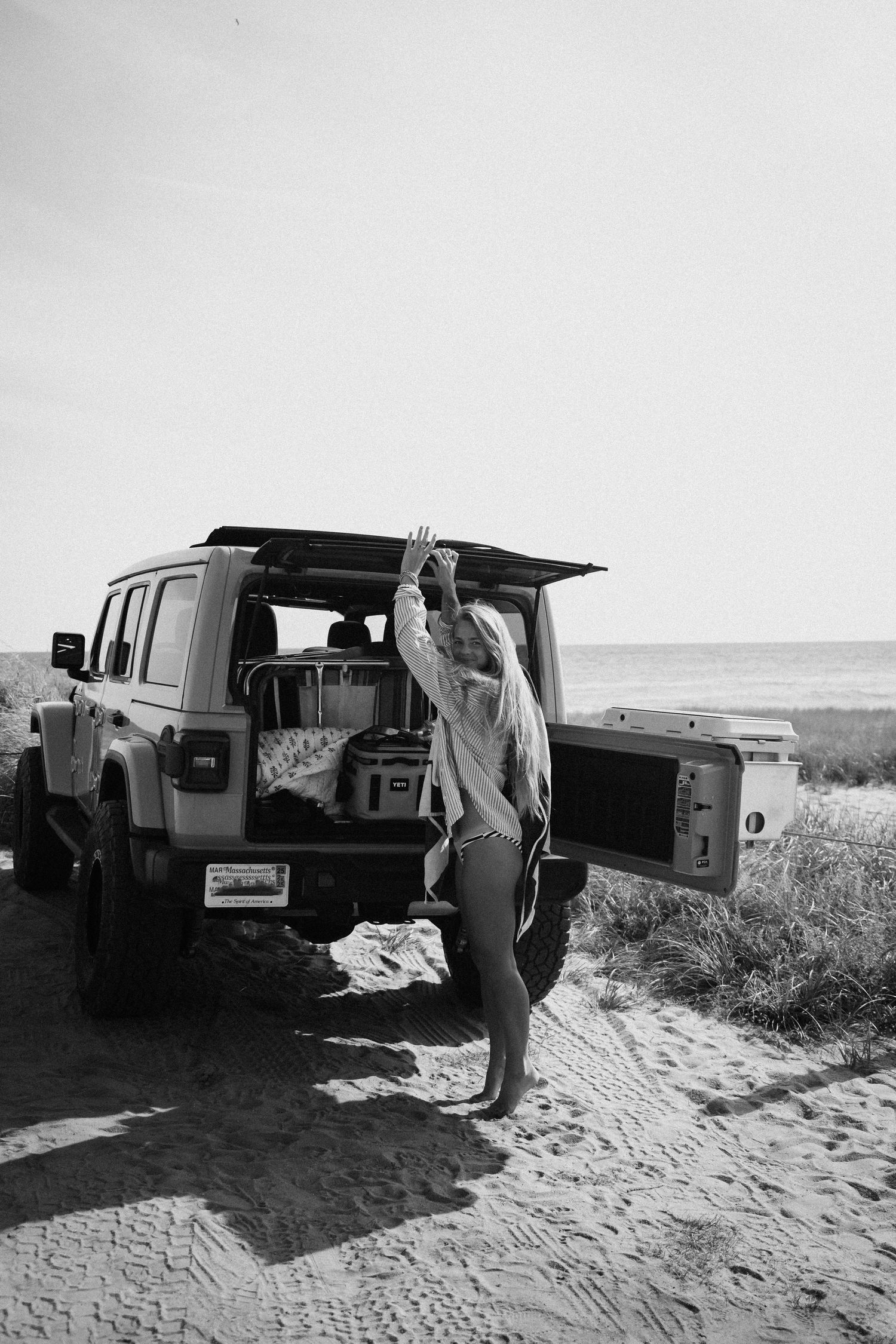 A sequence of black and white images showing vintage cars parked on a sandy beach.