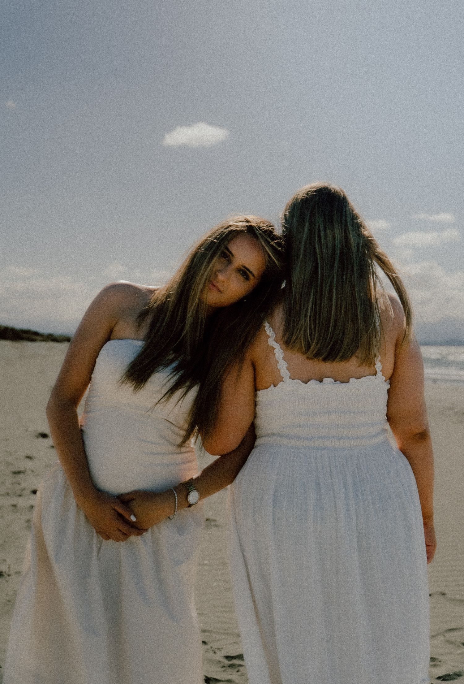 Person with long hair sits on grass overlooking coastal cliffs and ocean view.