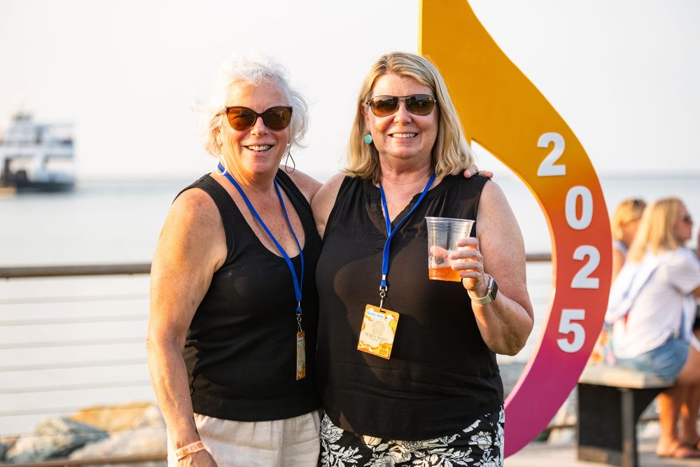 People enjoying a social gathering outdoors near a waterfront with drinks and sunny weather.