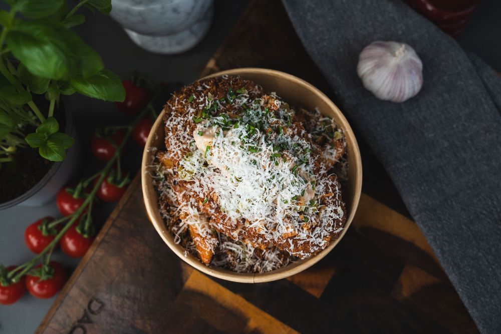 Homemade spaghetti and meatballs topped with fresh grated parmesan cheese and basil leaves on a dark table.