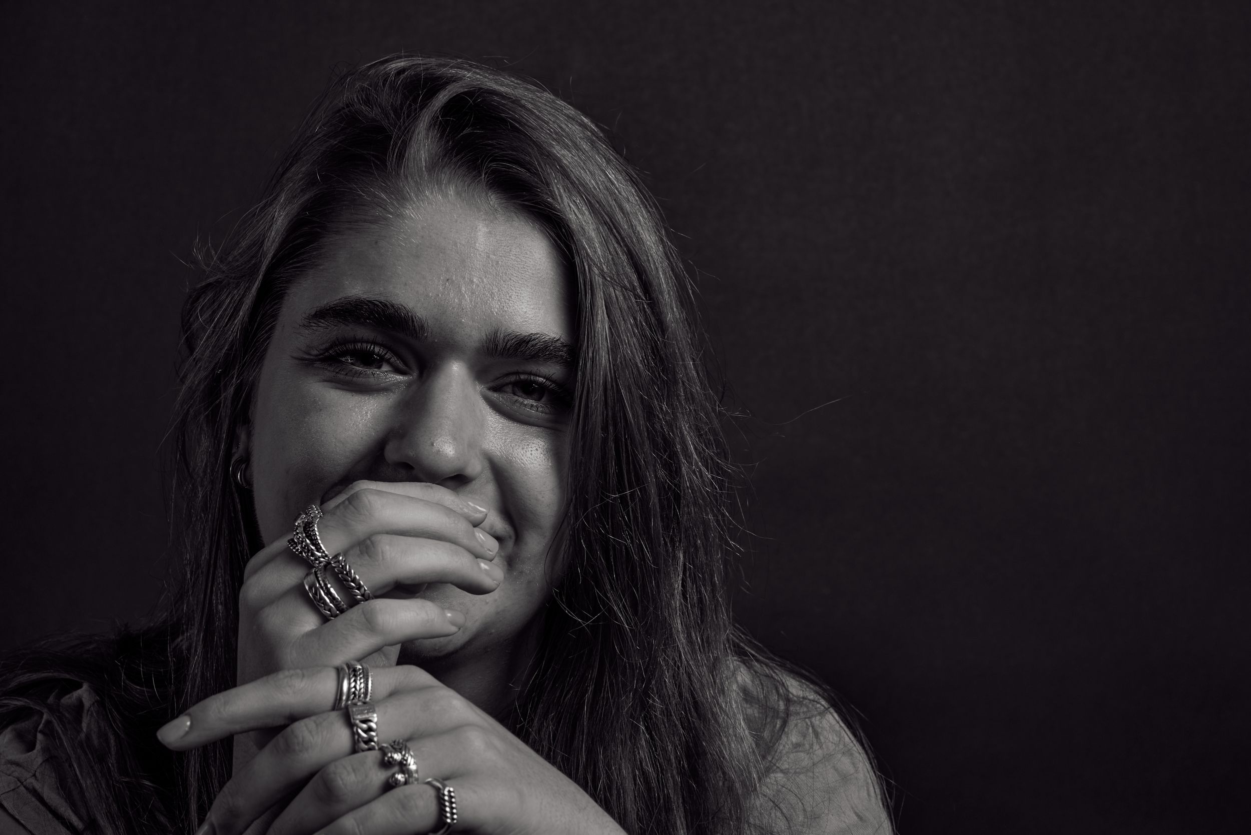 Zwart wit portret van een jonge vrouw met ringen om haar vingers