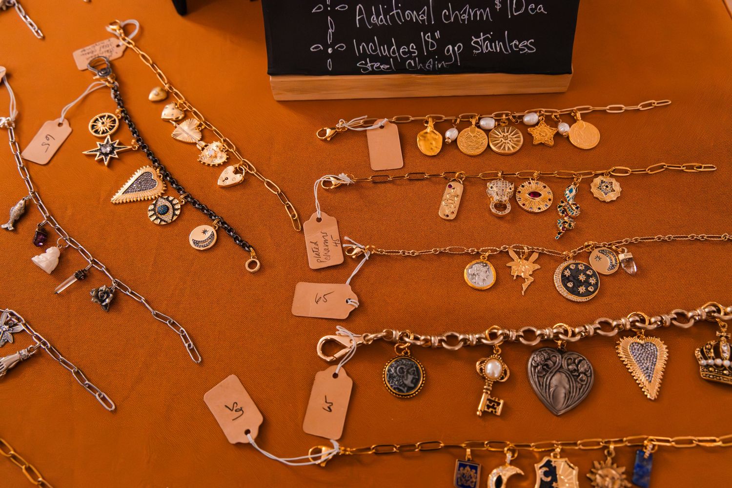 Close-up of antique keys and charms arranged on strings against orange wall.
