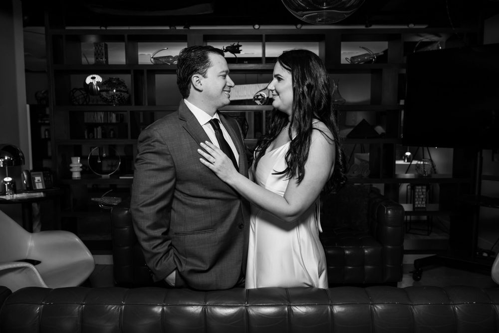 Black and white portrait of couple sharing intimate moment at elegant bar setting.
