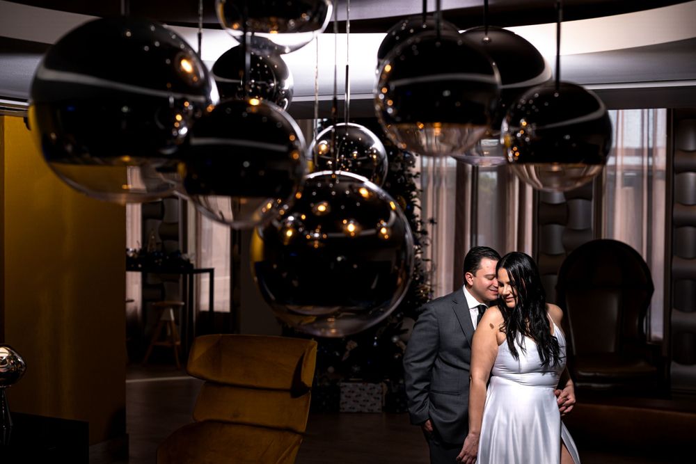 Couple shares tender moment beneath stylish black pendant lights in modern venue.