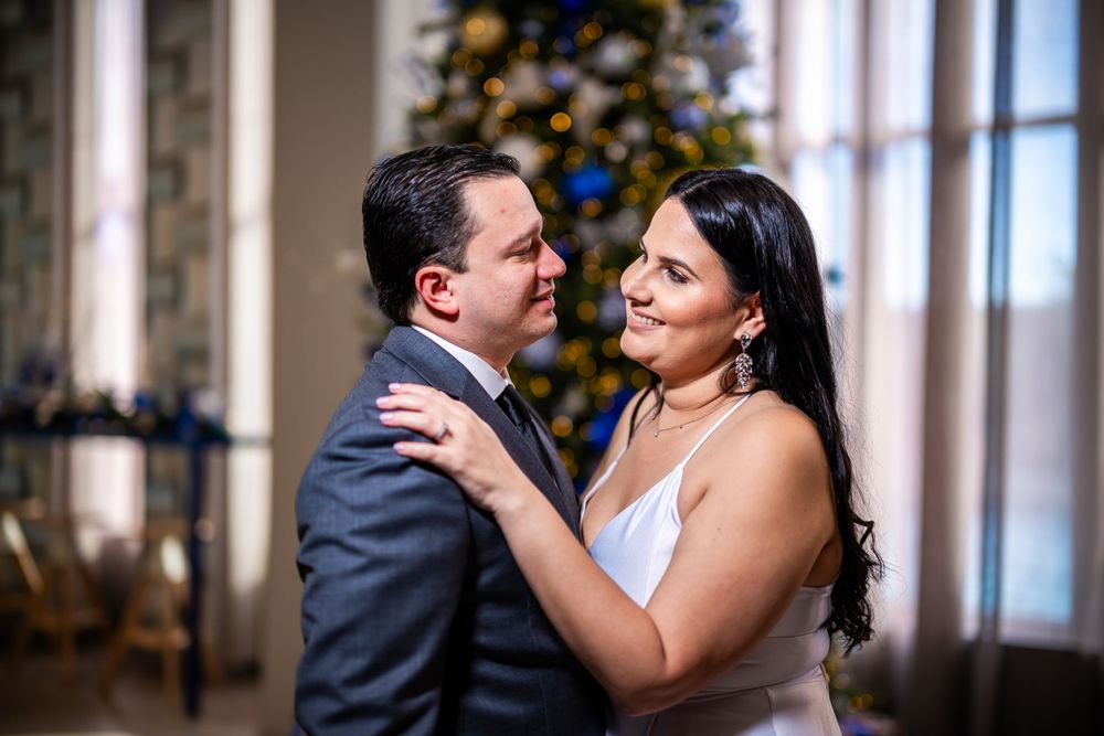 Couple in formal attire sharing intimate embrace in elegantly decorated room.
