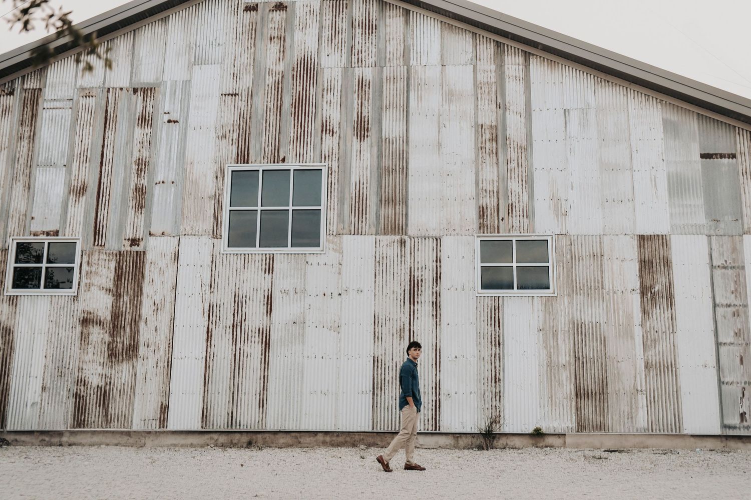 Senior guy portrait leaning against metal warehouse doors in downtown McKinney