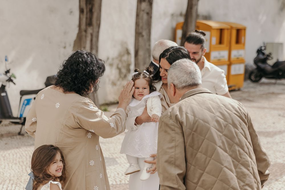 Family gathering outdoors as adults lovingly attend to a young girl dressed in white.