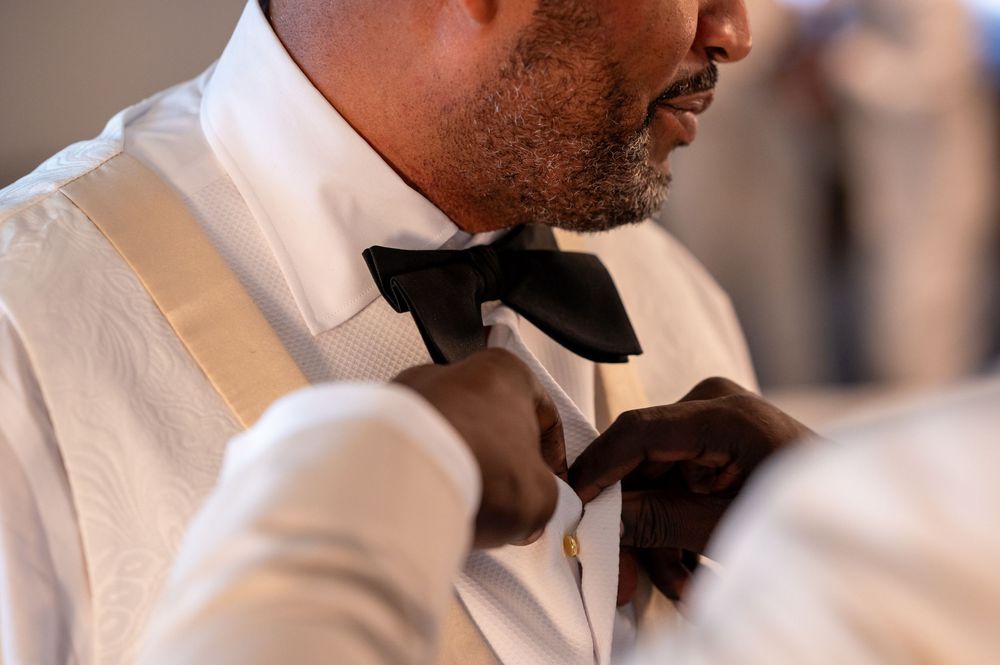 The best man fixes the bow tie of the groom.