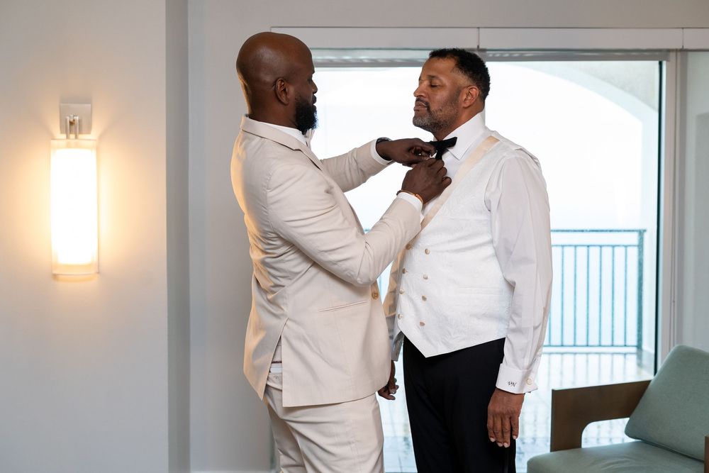 The best man assists the groom with his preparations.